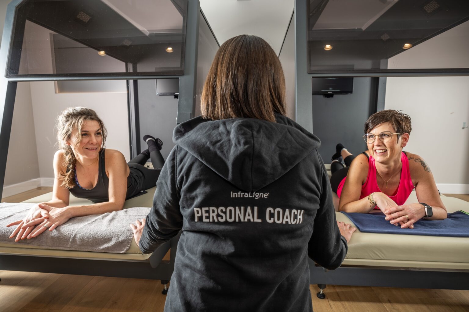 2 InfraLigne cabines met 2 tevreden klanten die uitleg krijgen van de InfraLigne Personal Coach